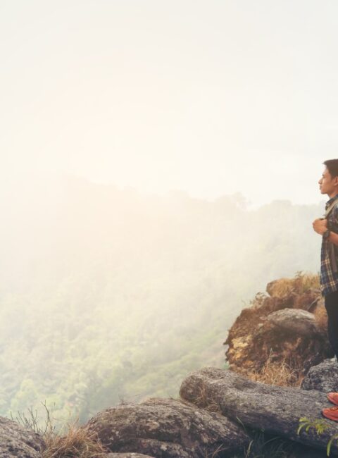 Man traveler with backpack on top of mountain. Travel Lifestyle concept.